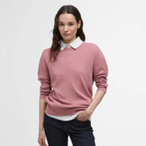 Woman wearing a pink sweater over a white shirt on a light grey background